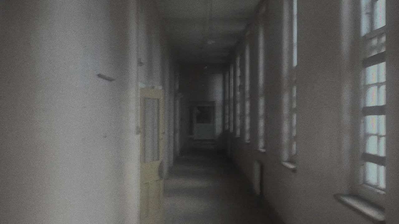 A long abandoned hospital corridor with a yellow door at the end